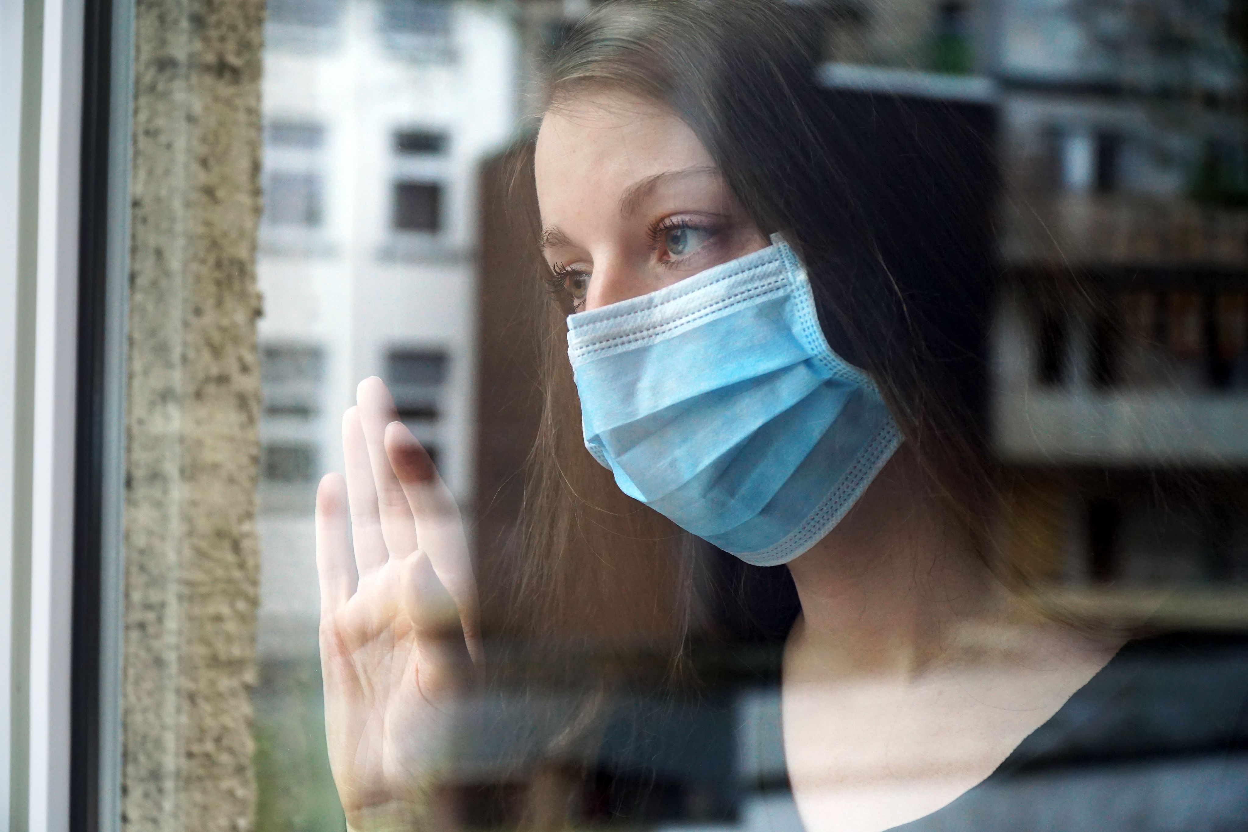 woman sitting on black chair in front of glass-panel window with white curtains